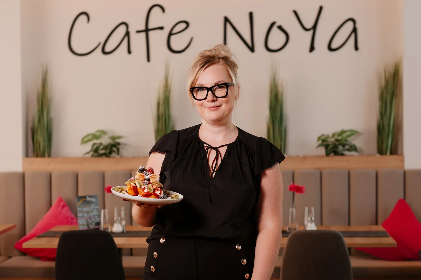 Mitarbeiterin des Café NoYa serviert einen Frühstücksteller