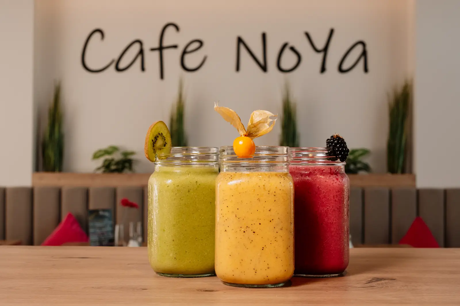 Drei Gläser mit frisch zubereiteten Smoothies und Früchten